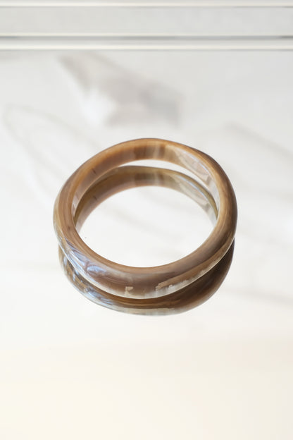 Natural horn bangle — styled overhead on marble surface with shadow detail