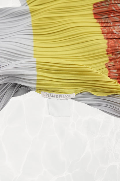 Pleats Please Issey Miyake x Mimi Yokoo carnation dress label detail: interior PLEATS PLEASE brand label at waist seam  with white and yellow pleated panels and carnation print, c. 2000