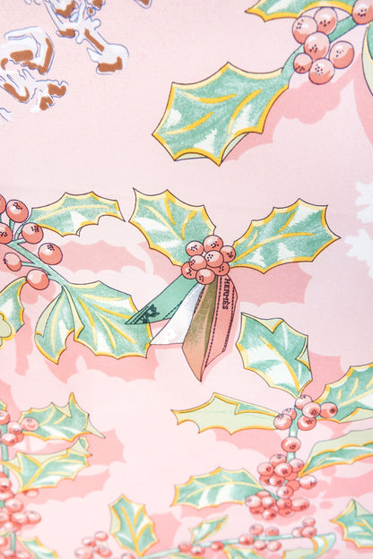 Hermès Neige d'Antan Carré 90 close-up: HERMÈS ribbon tied on illustrated holly and berry sprig, botanical winter motif on pink silk twill