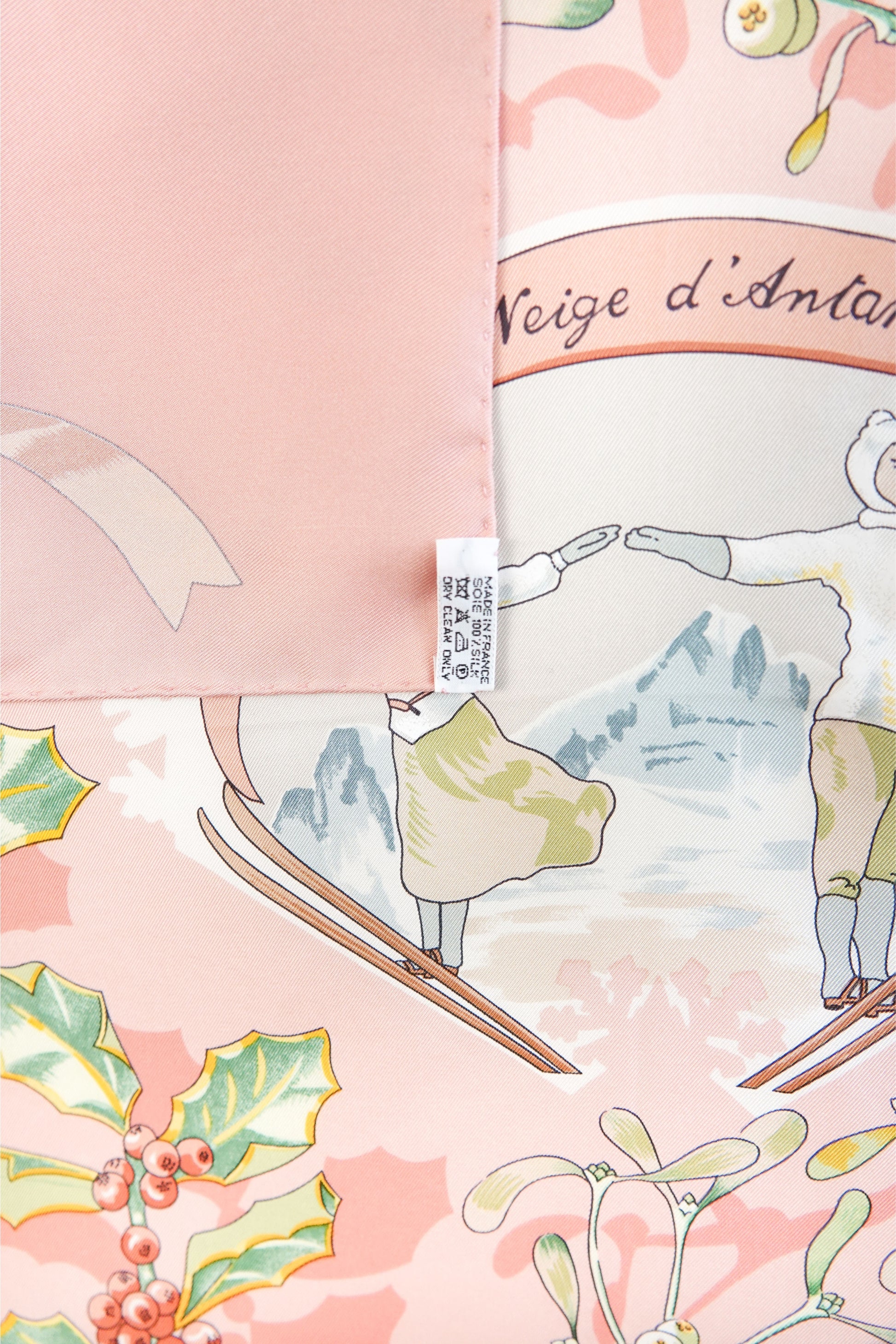 Hermès Neige d'Antan Carré 90 care label detail: Made in France, 100% silk, with skier motif and holly botanical on pink silk twill