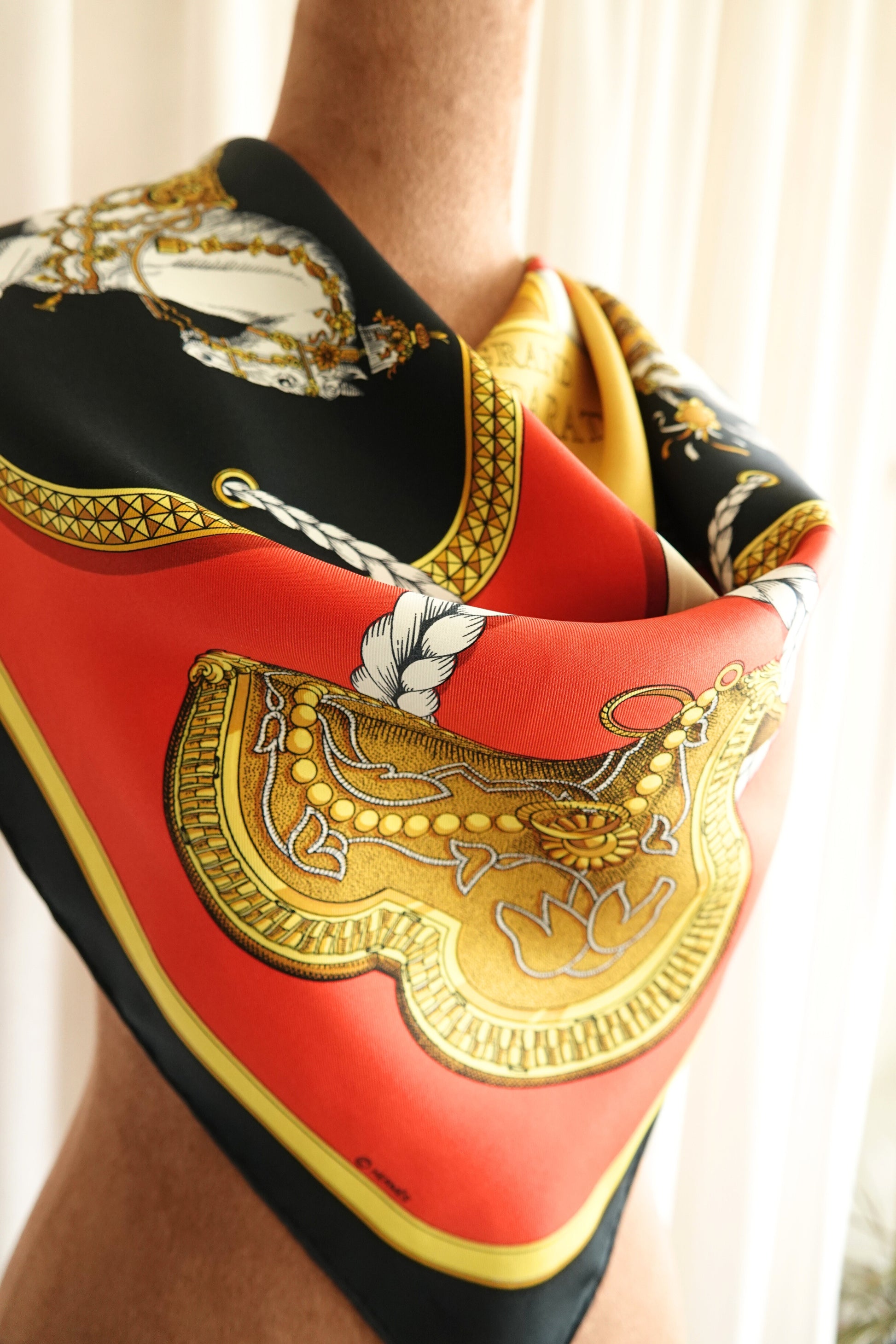 Hermès Grand Apparat Carré 90 close-up detail, gold equestrian emblem on red and black silk twill
