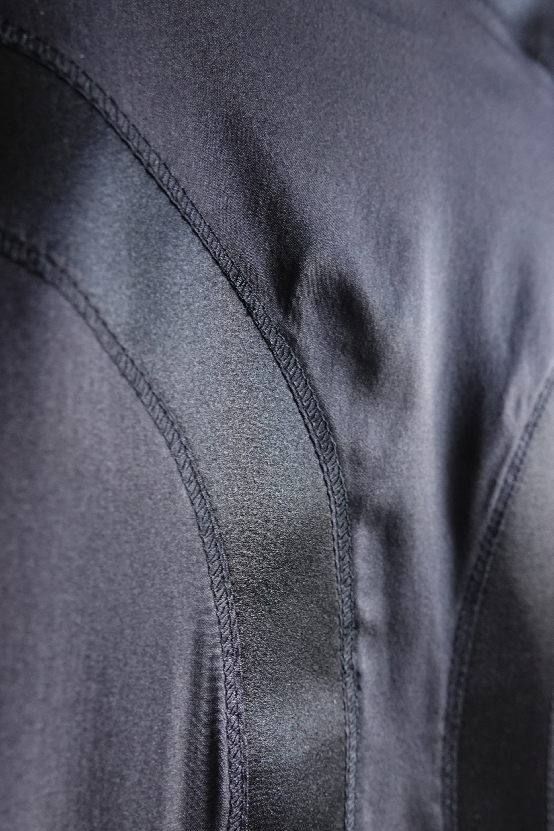 Tom Ford for Gucci FW03 black silk skirt construction detail: close-up of curved seam topstitching on bias-cut satin panel, showing tailoring quality and silk sheen, Fall 2003