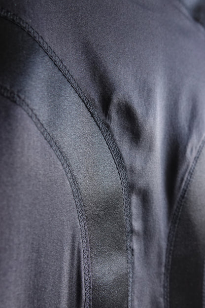 Tom Ford for Gucci FW03 black silk skirt construction detail: close-up of curved seam topstitching on bias-cut satin panel, showing tailoring quality and silk sheen, Fall 2003