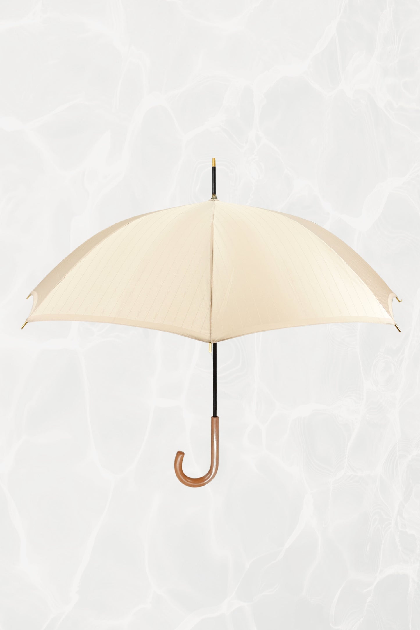Vintage YSL Yves Saint Laurent gold umbrella with embossed monogram: full view of closed umbrella showing the gold handle and overall elegant silhouette