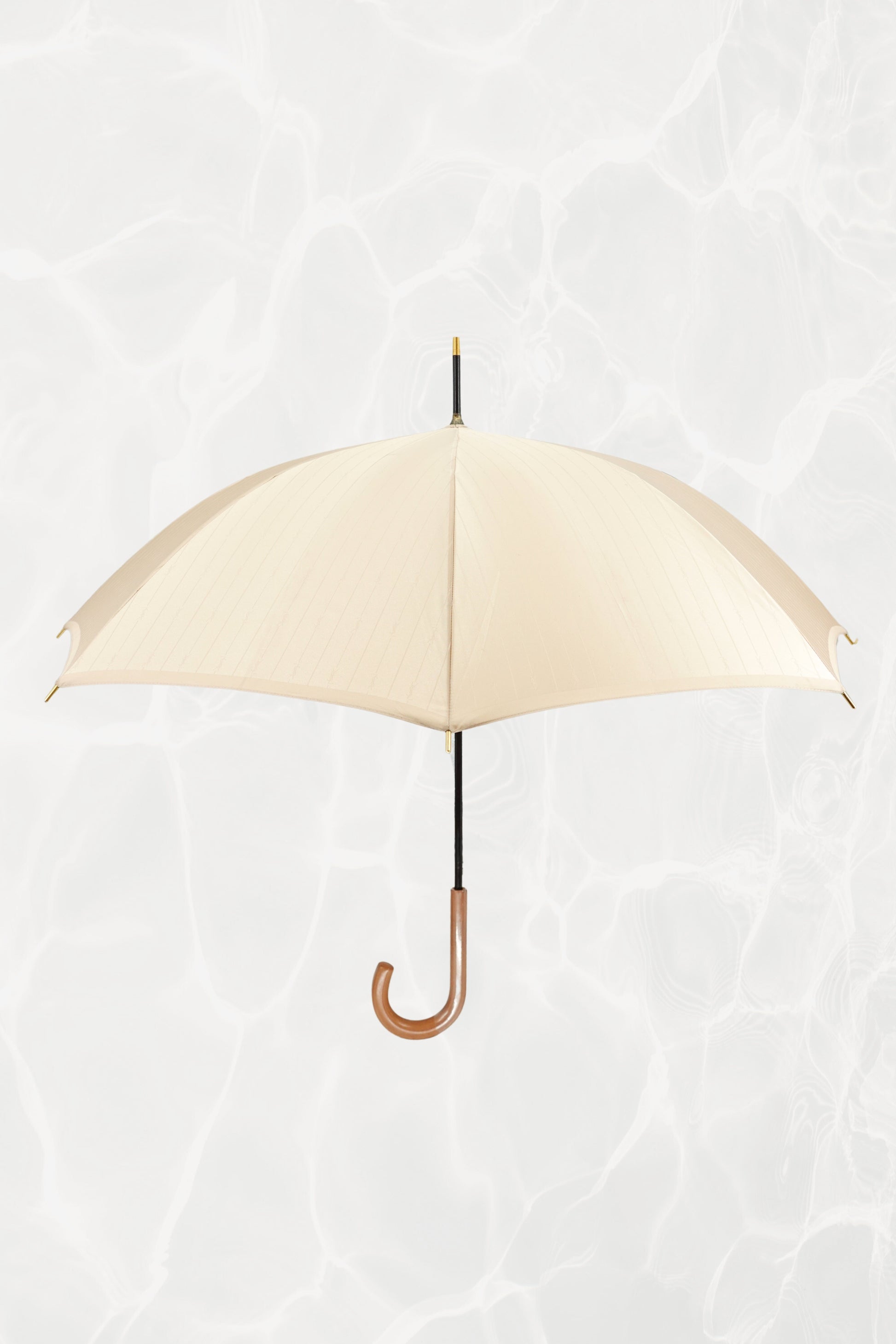 Vintage YSL Yves Saint Laurent gold umbrella with embossed monogram: full view of closed umbrella showing the gold handle and overall elegant silhouette