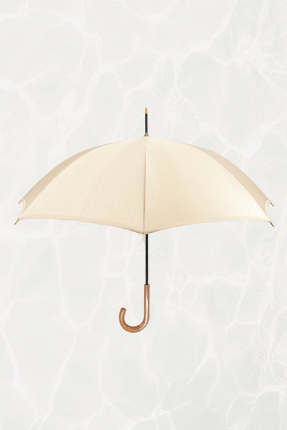 Vintage YSL Yves Saint Laurent gold umbrella with embossed monogram: full view of closed umbrella showing the gold handle and overall elegant silhouette