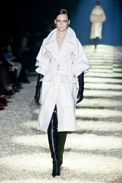 Tom Ford for Gucci AW03 white wool angora corset coat on runway: opening look with oversized collar, corset belt, black over-the-knee boots and long gloves, Gucci Fall Winter 2003