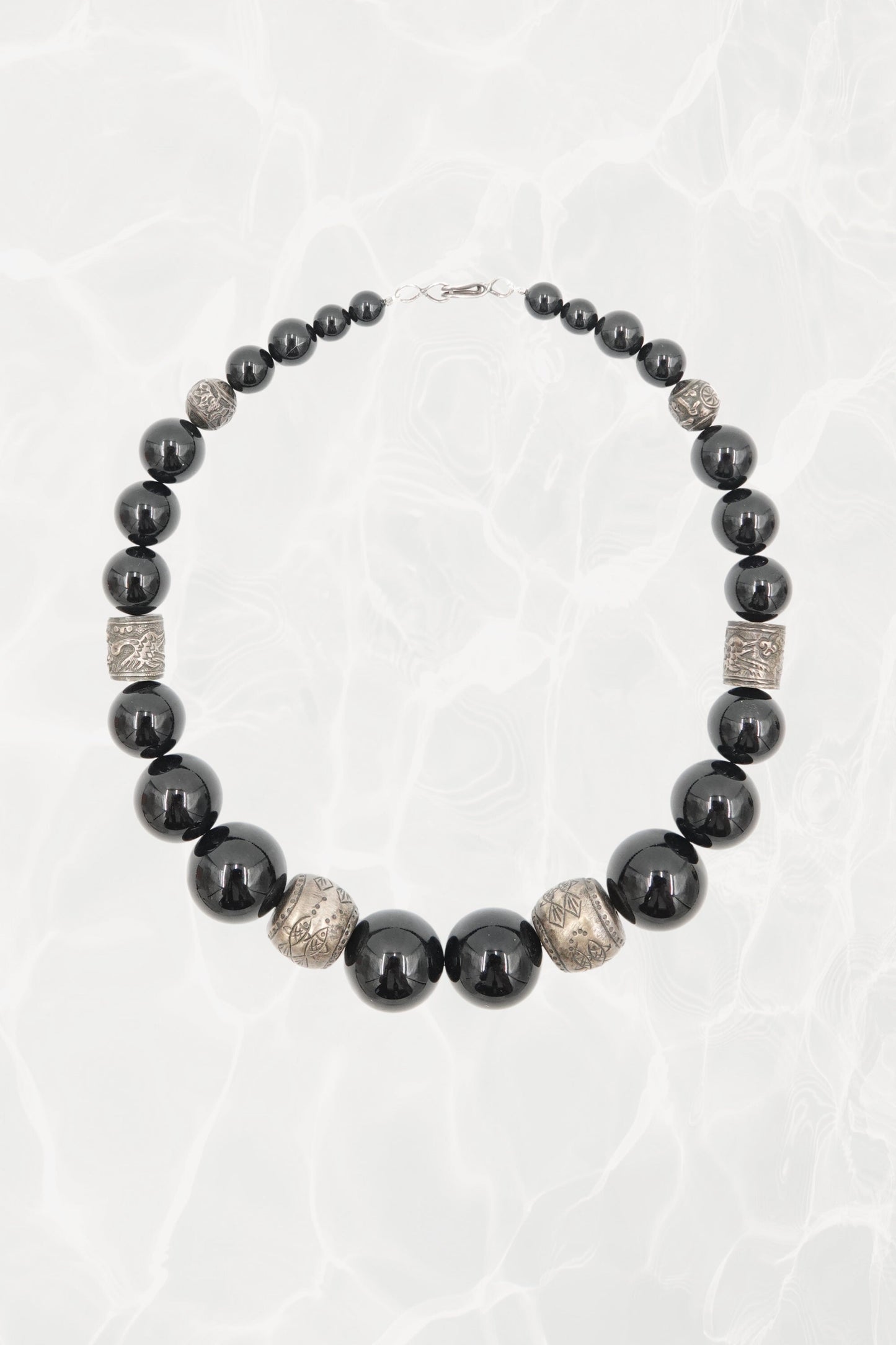 Vintage 1980s black onyx graduated beaded necklace with engraved silver spacers — full length on background