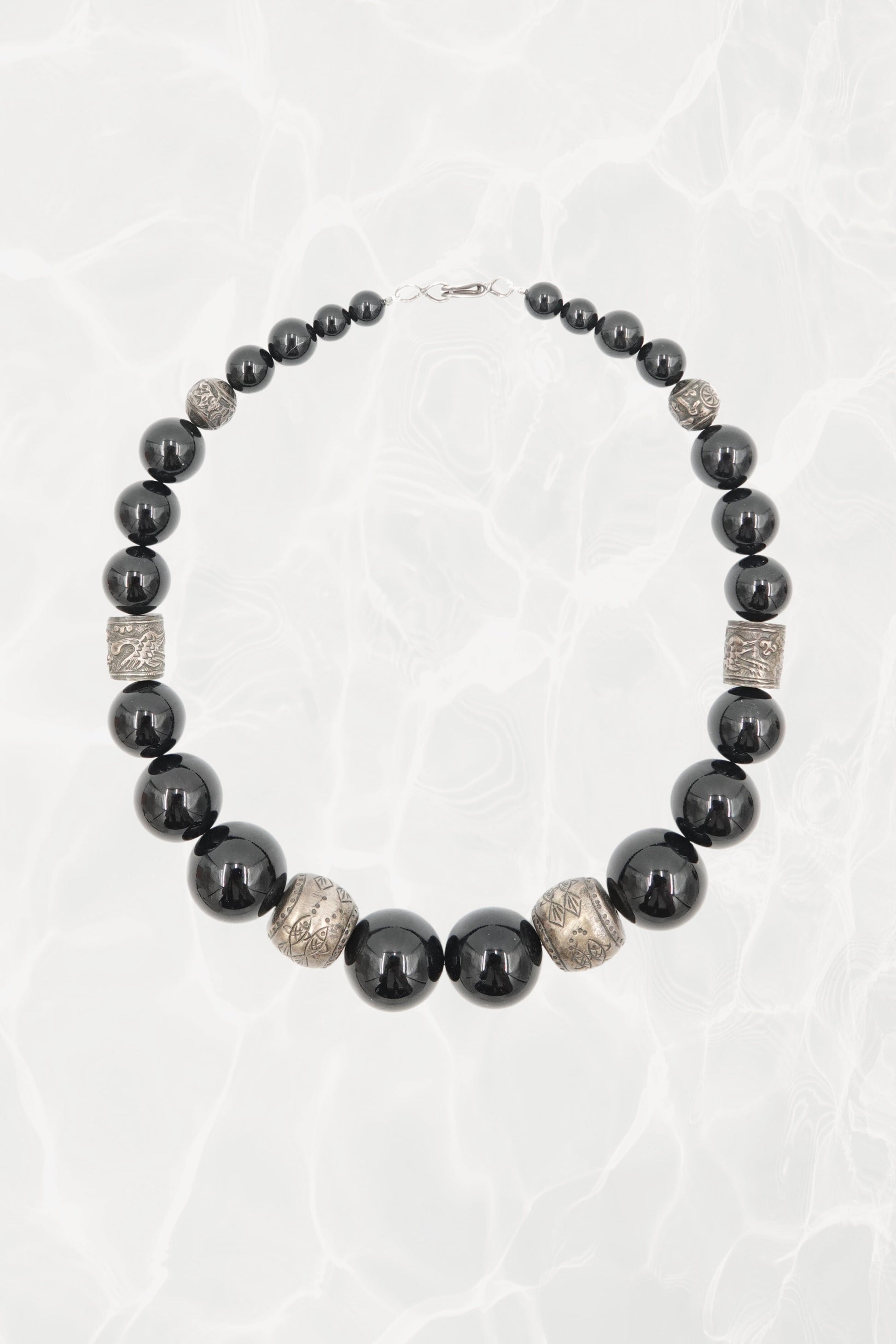 Vintage 1980s black onyx graduated beaded necklace with engraved silver spacers — full length on background